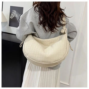 Detail of beige quilted half-moon tote with vertical textures and stylish knot strap
