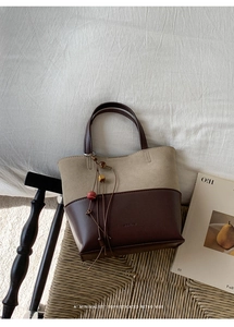 Detail of a two-tone bucket bag with long colorful tassels and embossed NOFILTER logo