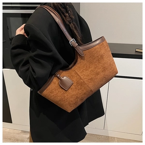 Detail of adjustable leather strap and silver metal buckle on a brown suede tote bag