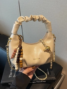 Chic beige ruched dumpling handbag with gold chain strap and wooden bead charm