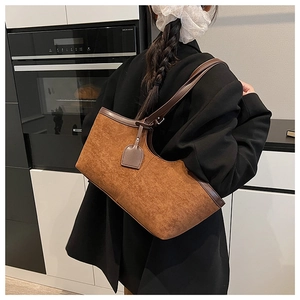 Detail of vintage brown suede tote bag featuring leather piping and a sleek shoulder strap