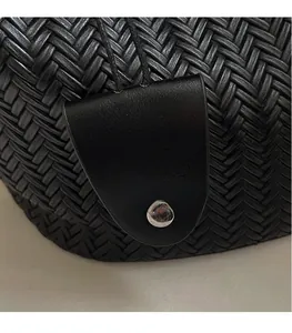 Gros plan d'un sac cabas noir tressé doté d'un bouton pression magnétique en métal argenté