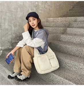 Gros plan du sac bandoulière en toile blanc cassé avec plusieurs poches utilitaires