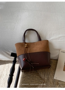 Detail of vintage bucket bag featuring brown suede stitching and decorative wooden beads