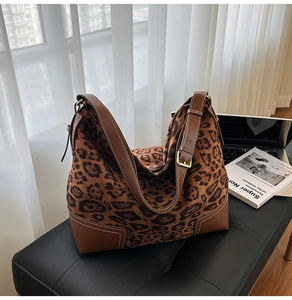Detail of leopard print tote bag with brown leather corner patches and golden hardware