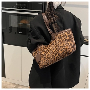 Detail of leopard print suede tote bag with brown leather strap and adjustable metal buckle