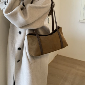 Brown suede pillow bag shown on model wearing a beige wool coat for a stylish autumn look