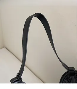 Gros plan sur la large bandoulière en cuir noir avec texture lisse et détail de nœud