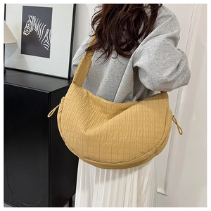 Detail of a ginger yellow pleated crescent bag with drawstring showing texture and fit