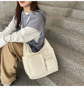 Détail d'un sac fourre-tout en toile beige à plusieurs poches porté en mode décontracté
