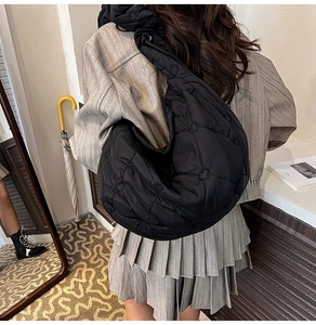 Detail view of black heart-quilted dumpling bag with a stylish pleated wide shoulder strap