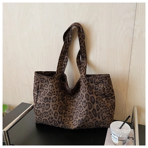 Close-up of leopard print canvas tote bag with dual straps on a display rack