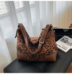 Detail of leopard print tote bag featuring leather corners and adjustable shoulder straps