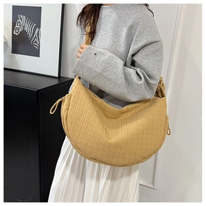 Detailed look at the ginger yellow quilted crescent tote bag shown on a model