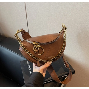 Gros plan du sac selle marron montrant la chaîne dorée et la texture raffinée