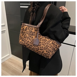 Detail of leopard print suede tote bag with brown leather straps on a black blazer