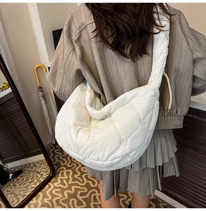 Detail view of white quilted heart pattern on a crescent-shaped nylon cloud bag for women