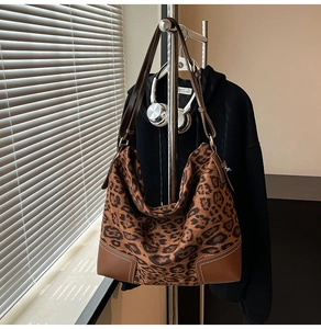 Detail of leopard print tote bag with brown leather trim and contrast stitching