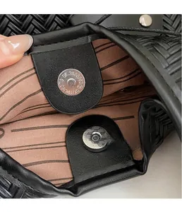 Gros plan du fermoir magnétique argenté sur le sac tissé noir avec doublure rayée