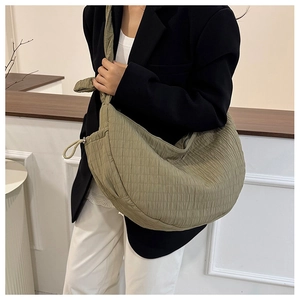 Macro shot of olive green quilted crescent bag with textured pleats and fabric strap