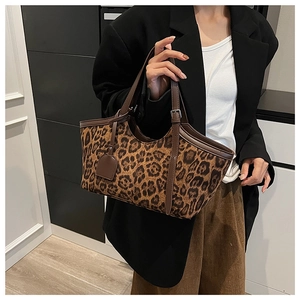Close-up of leopard print tote bag with brown leather handles and metal hardware detail