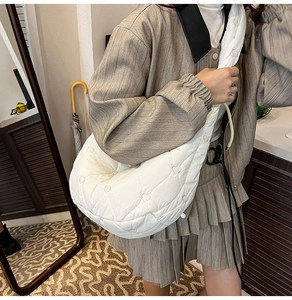 Detail of white quilted crescent bag with heart embroidery and soft nylon texture