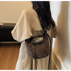 Detail of leopard print suede bucket bag with black leather flap shown on a model