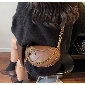 Gros plan d'un sac selle en cuir marron avec chaîne dorée et détail du logo Sunita & Fe