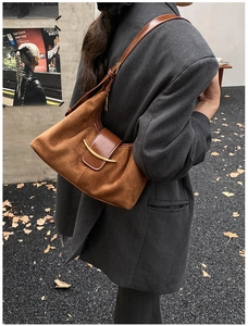 Détail d'un sac à bandoulière vintage en daim marron avec boucle en métal doré et lanière