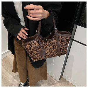 Close-up of leopard print tote bag featuring brown leather trim and metal handle buckle