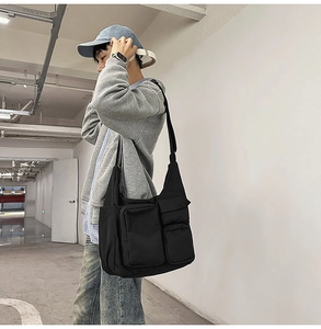 Détail du sac bandoulière en toile noire avec plusieurs poches et sangle réglable