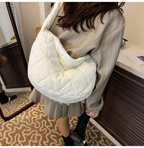 Detail view of heart-shaped quilting and soft padded texture on a white crossbody bag