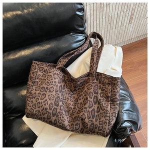 Close-up of leopard print tote bag texture and handles on a premium leather sofa