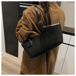 Detail of black suede tote bag with leather trim worn with brown corduroy blazer