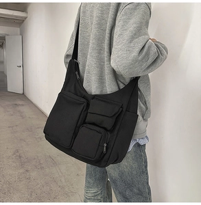 Gros plan d'un sac à bandoulière en toile noire à poches multiples porté par un modèle