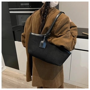 Shoulder bag detail showing matte black texture and faux leather strap on model