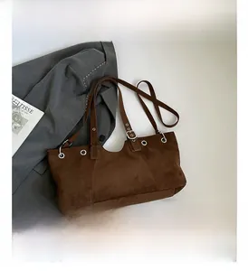 Detail view of brown suede tote bag featuring silver eyelets and a stylish V-cut design