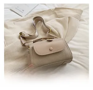 Dettaglio borsa beige con motivo litchi, finiture dorate e tracolla in tessuto largo