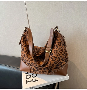 Close-up of leopard print tote bag with brown leather trim and golden metal buckles
