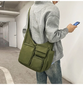 Vue détaillée du sac bandoulière en toile vert olive avec de multiples poches cargo