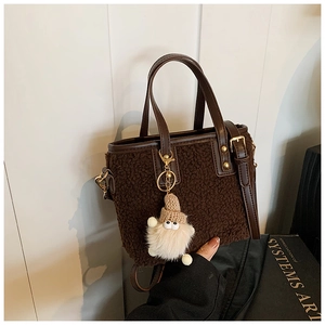 Close-up of deep brown plush bucket bag featuring soft fleece texture and leather strap