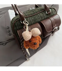 Detailed close-up of a brown teddy plush charm with plaid bow on a vintage Boston bag