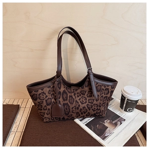 Detailed view of leopard print tote bag with brown leather handles and side tag detail