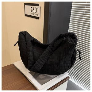 Detail shot of black hobo bag with bubble pleated texture on a magazine over wooden desk