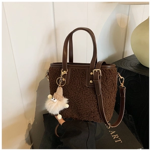 Macro view of dark brown plush bucket bag texture with a cute dwarf pendant accessory