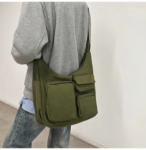 Détail du grand sac bandoulière en toile vert olive avec plusieurs poches utilitaires