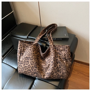 Close-up of leopard print canvas tote bag with long handles on black leather sofa