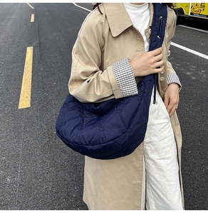 Detail of dark blue quilted shoulder bag featuring heart pattern stitching and wide strap