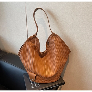 Detailed view of brown woven leather tote with V-cut opening on design books