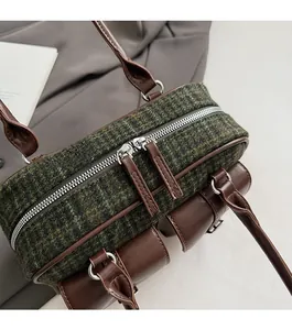 Detail of green tweed bowling bag with dual zippers and brown faux leather stitching